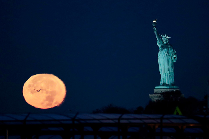 The supermoon appears near the Statue of Liberty, Monday, Nov. 14, 2016, in New York.