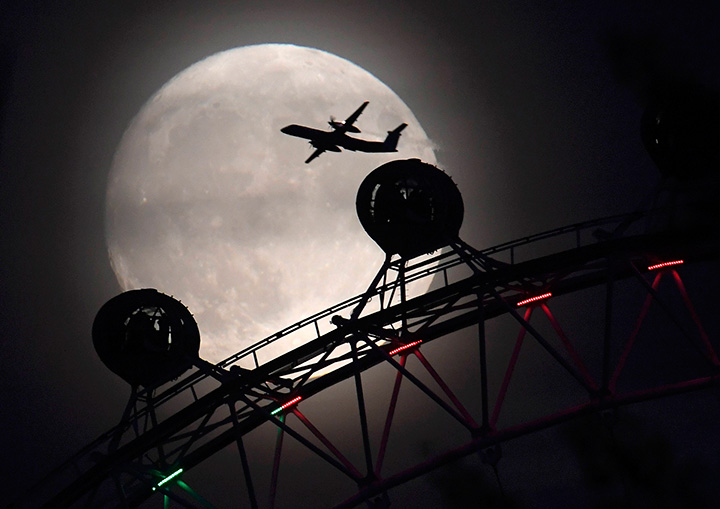 A plane flies past the London Eye wheel as the supermoon begins to rise in London, November 13, 2016.
