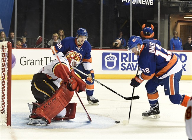 Calgary Flames goalie Brian Elliott (1) blocks a shot on goal by New York Islanders left wing Josh Bailey (12) as Islanders left wing Nikolay Kulemin (86) looks on in the second period of an NHL hockey game in New York, Monday, Nov. 28, 2016. 