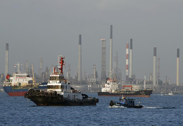 Vessels pass an oil refinery in the waters off the southern coast of Singapore, February 26, 2016. 