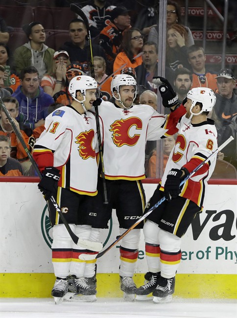 Calgary Flames' Mikael Backlund, from left, TJ Brodie and Dennis Wideman celebrate after Brodie's goal during the first period of an NHL hockey game against the Philadelphia Flyers, Sunday, Nov. 27, 2016, in Philadelphia. 