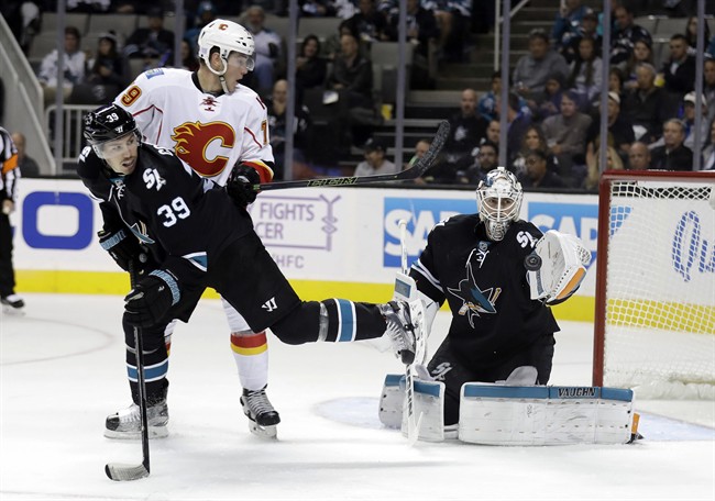 San Jose Sharks goalie Martin Jones, right, stops a shot next to Calgary Flames' Micheal Ferland, center, and Sharks' Logan Couture (39) during the second period of an NHL hockey game Thursday, Nov. 3, 2016, in San Jose, Calif. 