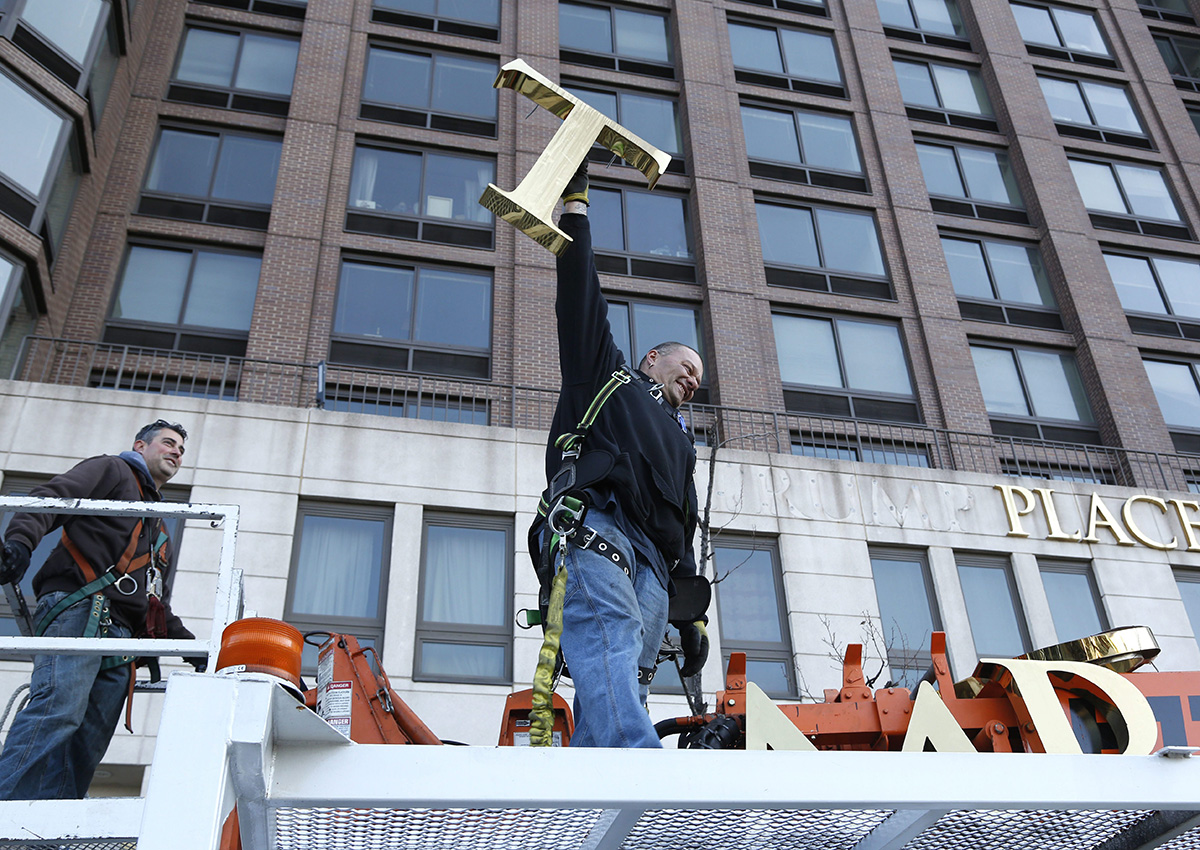 A workman holds up the letter "T" as they remove the letters from a building formerly known as Trump Place in New York, Wednesday, Nov. 16, 2016. 