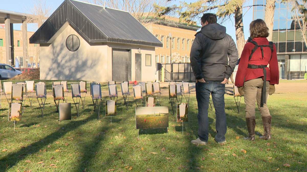 Two people look at the 65 grave site photos of the Saskatchewan born soldier who died in the D-Day Invasion.