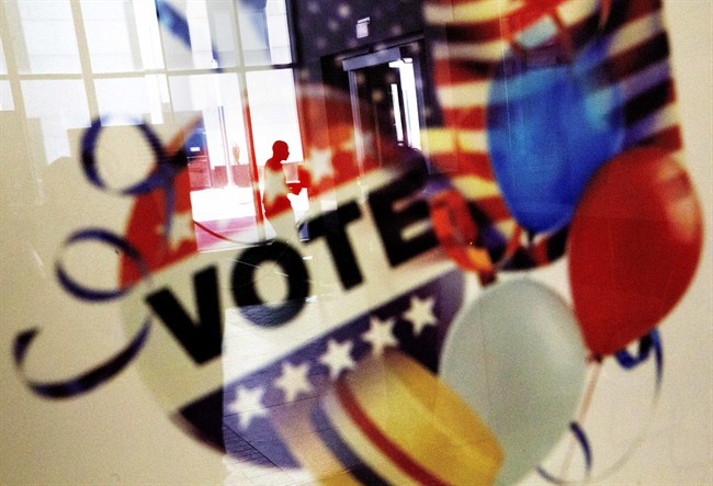 A voter is reflected in the glass frame of a poster while leaving a polling site in Atlanta in this Nov. 1, 2016 file photo.