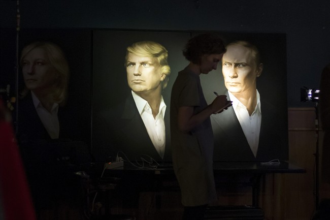 A journalist writes a material as she watches a live telecast of the U.S. presidential election standing at portraits of U.S. presidential candidate Donald Trump and Russian President Vladimir Putin in the Union Jack pub in Moscow, Russia, Wednesday, Nov. 9, 2016.