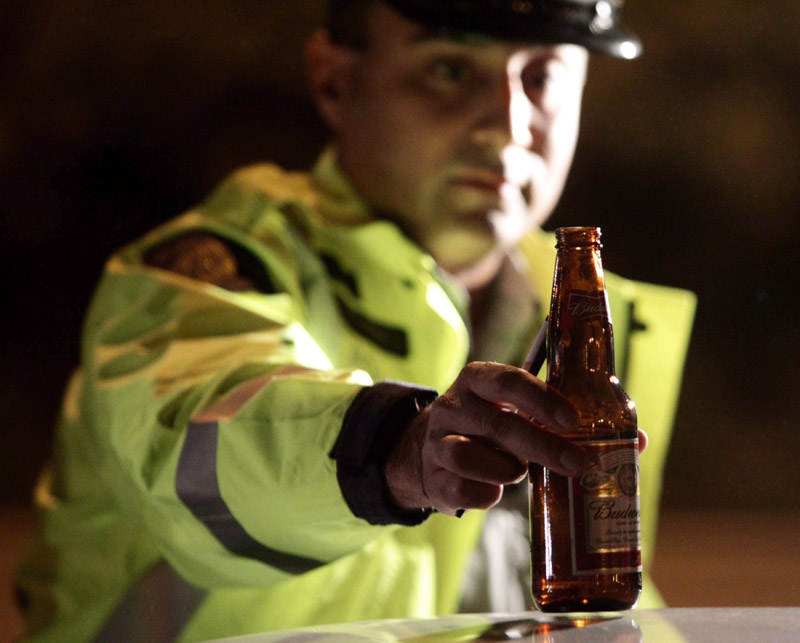 RCMP Cnst. Faz Majid removes an open bottle of beer from a motorist's car during a roadside check in Surrey, B.C. on September 24, 2010. 
