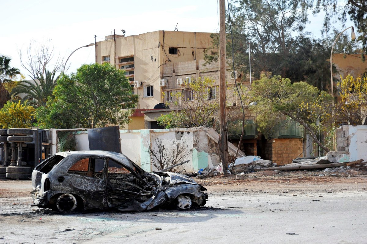 This March 10, 2016 file photo shows damaged buildings and a burned car south-west of Benghazi, Libya.

