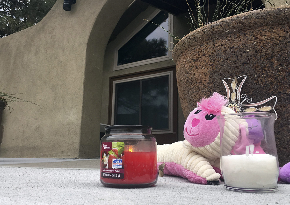 A small memorial of a stuffed animal and candles left by neighbors sits outside an Albuquerque, N.M, home on Tuesday, Dec. 6, 2016, a day after police say a man broke in and fatally shot three children. 