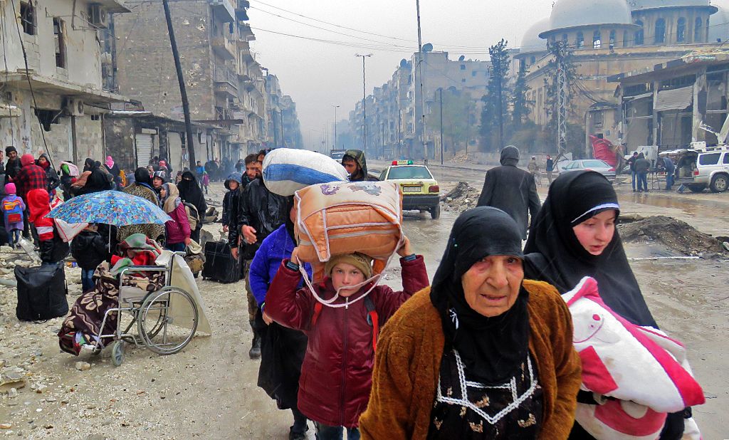 Syrian residents, fleeing violence in the restive Bustan al-Qasr neighbourhood, arrive in Aleppo’s Fardos neighbourhood on December 13, 2016, after regime troops retook the area from rebel fighters.