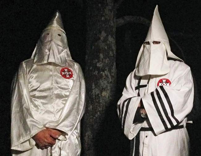 In this Friday, Dec. 2, 2016 photo, two masked Ku Klux Klansmen stand on a muddy dirt road during an interview near Pelham, N.C. (AP Photo/Jay Reeves).