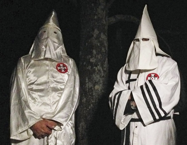 In this Friday, Dec. 2, 2016 photo, two masked Ku Klux Klansmen stand on a muddy dirt road during an interview near Pelham, N.C. (AP Photo/Jay Reeves).