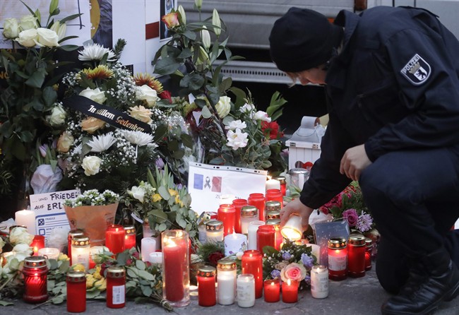 FILE - In this Dec. 20, 2016 file photo a police officer lights a candle in Berlin, Germany the day after a truck ran into a crowded Christmas market nearby. German prosecutors say they've detained a Tunisian man they think may have been involved in last week's truck attack on a Christmas market in Berlin. Federal prosecutors said Wednesday Dec. 28, 2016 the 40-year-old was detained during a search of his home and business. (AP Photo/Matthias Schrader,file).