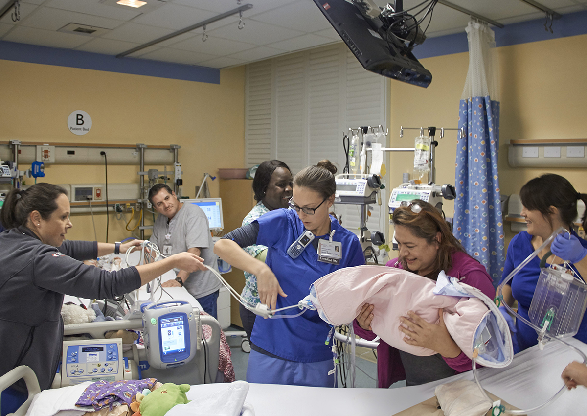 In this Monday, Dec. 12, 2016, photo provided by the Lucile Packard Children’s Hospital Stanford, Pediatric Intensive Care Unit members of the girls’ care team position Erika’s bed so that the twins’ mother, Aida Sandoval, second from right, could pick up her daughter, Erika, from her bed and place her next to her sister Eva, partially seen at left with her father, Arturo Sandoval, in Palo Alto, Calif.