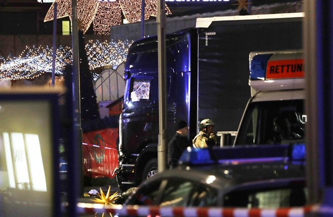 Police stand beside a damaged truck which ran into crowded Christmas market in Berliin Berlin, Germany, Monday, Dec. 19, 2016. (AP Photo/Michael Sohn).