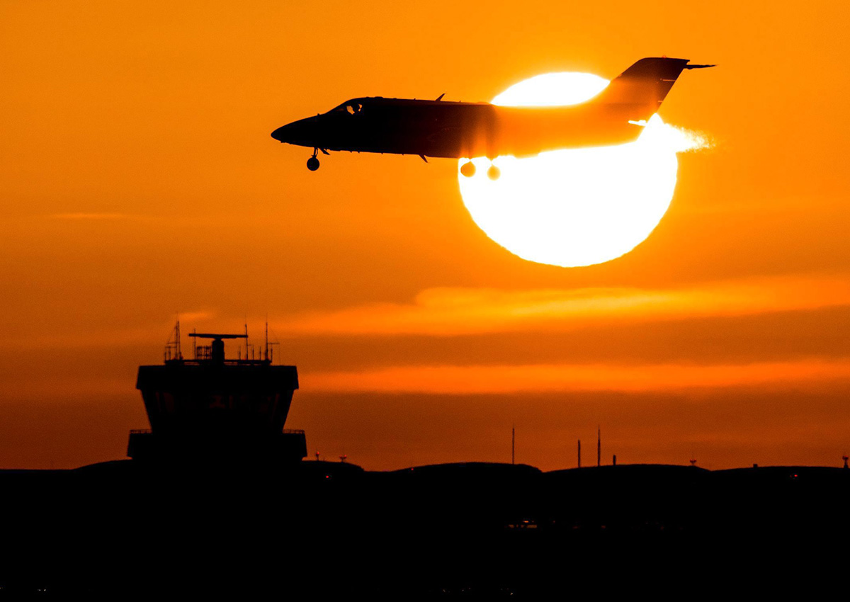 Silhouette of a plane in front of a sunset.