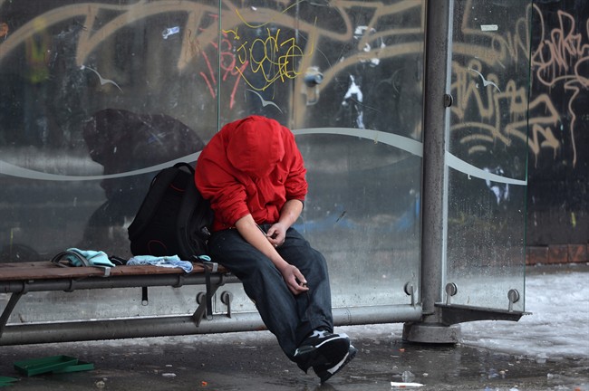 A man injects himself at a bus shelter in Vancouver's Downtown Eastside, Monday, Dec.19, 2016.