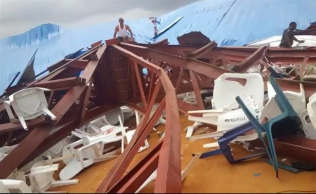 In this image made from video taken on Saturday, Dec. 10, 2016, local people survey the scene after a church roof collapsed in Uyo, Nigeria. Metal girders and the roof of a crowded church collapsed onto worshippers in southern Nigeria, killing at least 160 people with the toll likely to rise, a hospital director said Sunday. Mortuaries in the city of Uyo are overflowing from Saturday's tragedy, medical director Etete Peters of the University of Uyo Teaching Hospital told The Associated Press. 