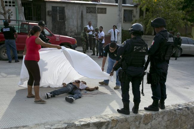 A forensic officer helps a woman place a sheet over the body of Alejandro Gallardo Perez, 23, after he was shot dead near his home in San Agustin, on the outskirts of Acapulco, in the Mexican state of Guerrero, in this April 15, 2016 file photo.
