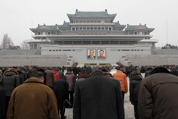 People offer three minutes of silence in front of portraits of the late leaders Kim Il Sung, left, and Kim Jong Il at the Kim Il Sung Square in Pyongyang, North Korea, Saturday, Dec. 17, 2016, to mark the fifth anniversary of Kim Jong Il's death. 