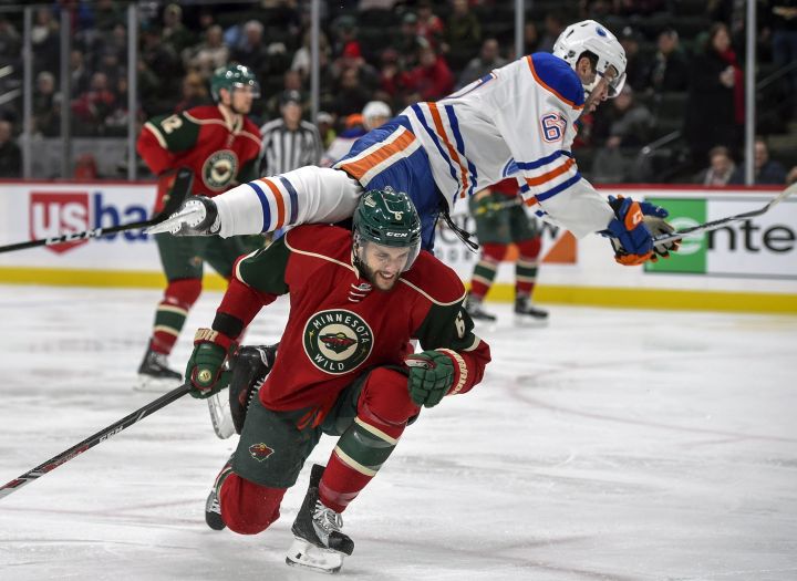 Edmonton Oilers' Benoit Pouliot flies over the top of Minnesota Wild's defenseman Marco Scandella, bottom, during the second period of an NHL hockey game, Friday, Dec. 9, 2016, in St. Paul, Minn. 