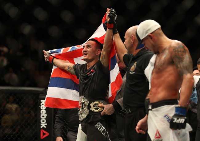Max Holloway celebrates after defeating Anthony Pettis, right, to win the interim featherweight title during the main event of UFC 206 at the Air Canada Centre in Toronto, Ont., Dec. 10, 2016.