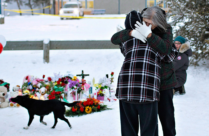 Residents console each other at a memorial near the La Loche Community School in Saskatchewan on Jan. 24, 2016 after four people were shot and killed at the school.