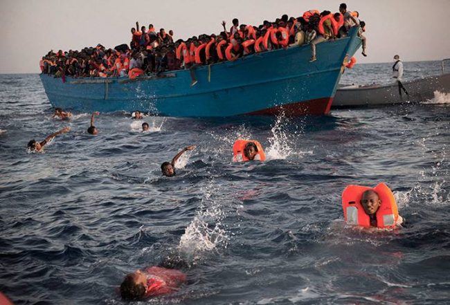 Migrants jump into the water from a crowded wooden boat as they are helped by members of an NGO during a rescue operation in the Mediterranean Sea, just north of Libya on Aug. 29, 2016.