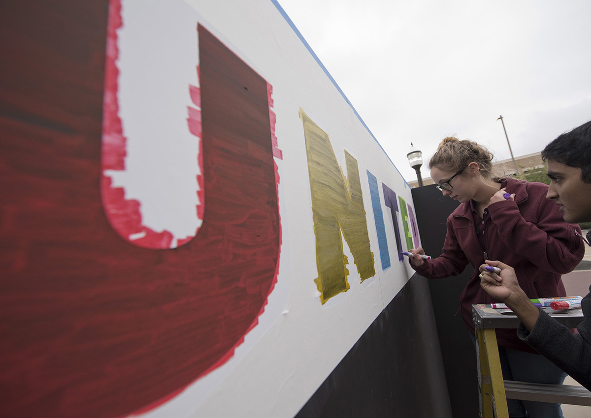 Texas A&M students Brendan D'Souza, right, and Sarah Minton paint a stencil on the "Expression Wall" put up in front of Kyle Field, Tuesday, Dec. 6, 2016, in College Station, Texas, before the university's "Aggies United" event.  