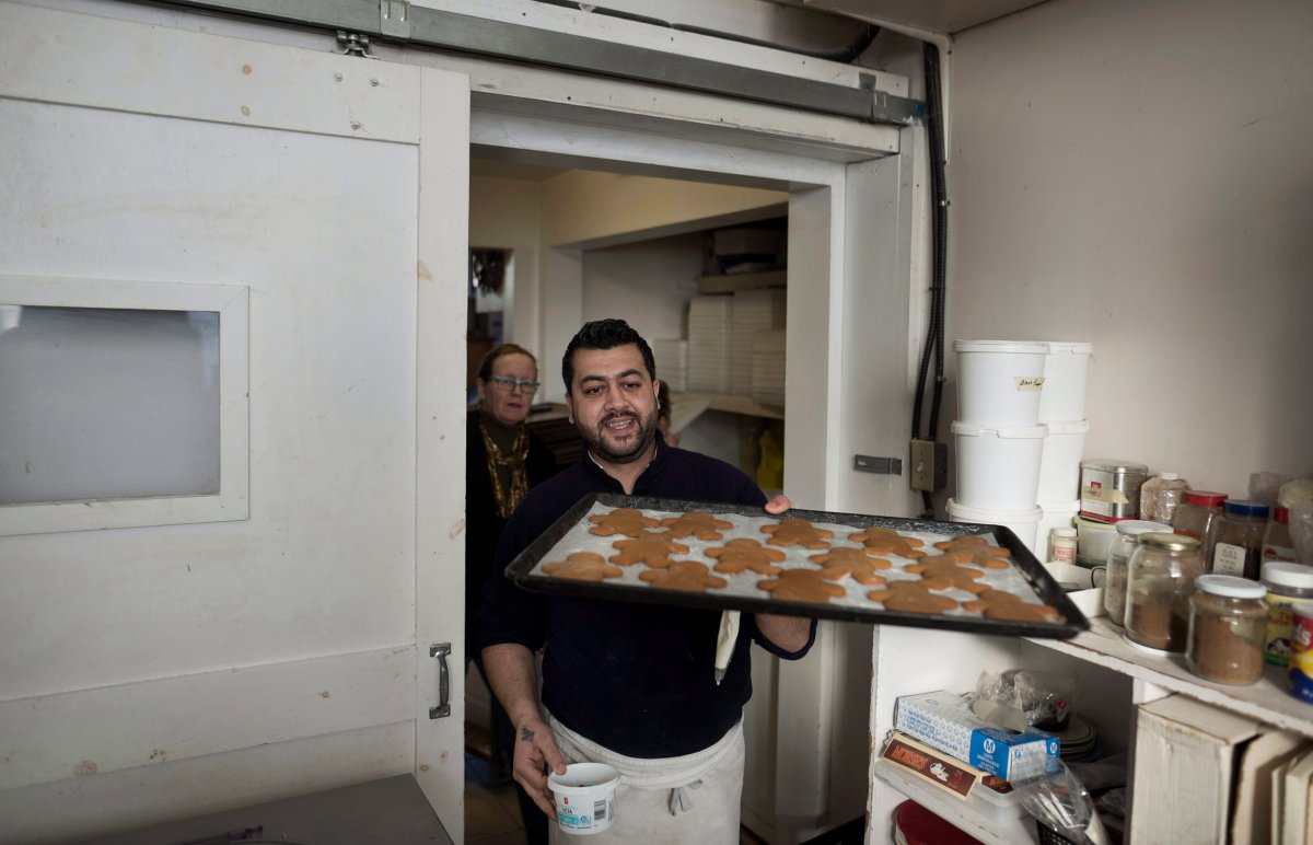Syrian refugee Ruwad Al Badin carries a tray of gingerbread men while working with Laura Mulrooney, co-owner of Julien's Bakery, at the company's production facility in Chester, N.S. on Tuesday, December 20, 2016. 