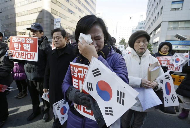 A protester supporting South Korean President Park Geun-hye weeps as she listens to the national anthem during a rally opposing the impeachment of South Korean President Park Geun-hye in front of the ruling Saenuri Party headquarters in Seoul, South Korea, Tuesday, Dec. 6, 2016. South Korea is entering potentially one of the most momentous weeks in its recent political history, with impeachment looming for Park as ruling party dissenters align with the opposition in a strengthening effort to force her out. The letters read "Oppose the impeachment. " (AP Photo/Ahn Young-joon).