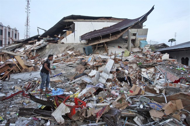 An Acehnese man and a police officer survey the damage after an earthquake in Ulhee Glee, Aceh province, Indonesia, Thursday, Dec. 8, 2016. Thousands of people in the Indonesian province of Aceh took refuge for the night in mosques and temporary shelters after a strong earthquake Wednesday killed a large number of people and destroyed dozens of buildings. (AP Photo/Binsar Bakkara).