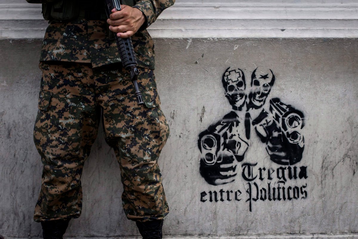 In this June 14, 2016 photo, a soldier stands next to a stenciled graffiti that reads in Spanish "Truce between politicians" painted on the main walls of the National Palace in San Salvador, El Salvador. After becoming the world's murder capital last year and posting an equally bloody start to 2016, El Salvador has seen its monthly homicide rates fall by about half.