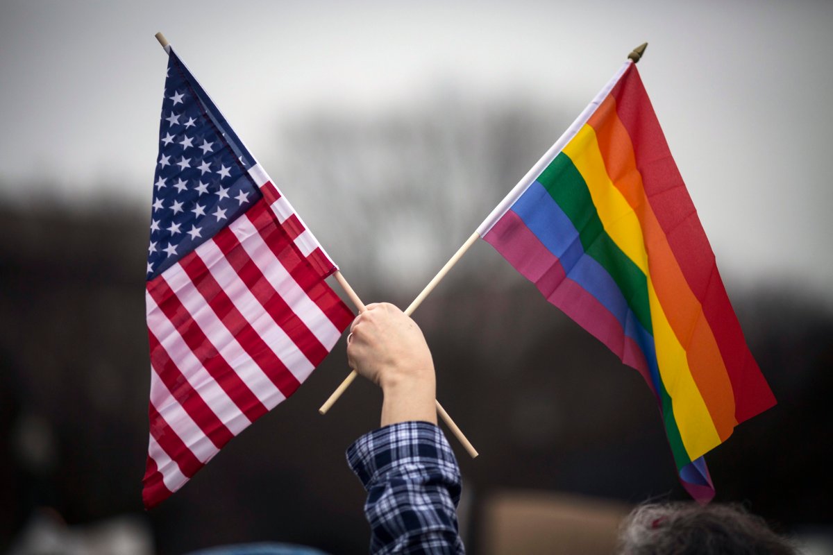 A participant holds both the US national flag (L) and the LGBT community's symbolic  Rainbow flag (R) as people arrive on the mall for the Women's March on Washington in Washington, D.C. on Jan. 21, 2017.