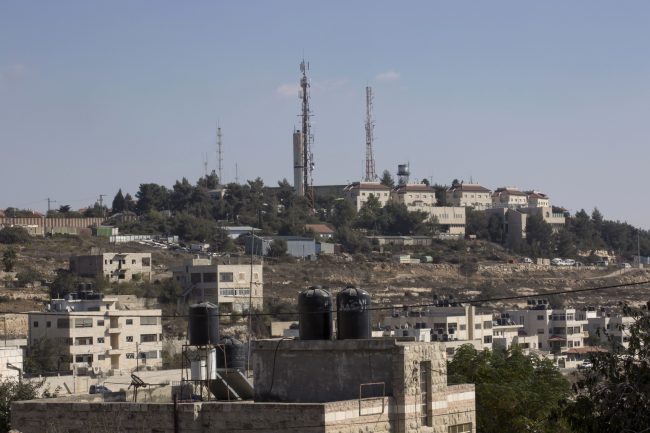 This photo shows part of the Israeli settlement of Psagot, background, overlooking Palestinian houses, in a suburb of the West Bank city of Ramallah, Oct. 24, 2016.
