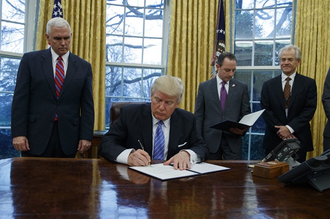 President Donald Trump signs an executive order to withdraw the U.S. from the 12-nation Trans-Pacific Partnership trade pact agreed to under the Obama administration, Monday, Jan. 23, 2017, in the Oval Office of the White House in Washington.