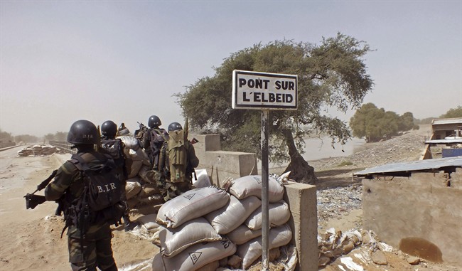 FILE - In this Wednesday, Feb. 25, 2015, file photo, Cameroon soldiers stand guard at a lookout post as they take part in operations against the Islamic extremists group Boko Haram, their guard post is on Elbeid bridge, left rear, that separates northern Cameroon form Nigeria's Borno state near the village of Fotokol, Cameroon.