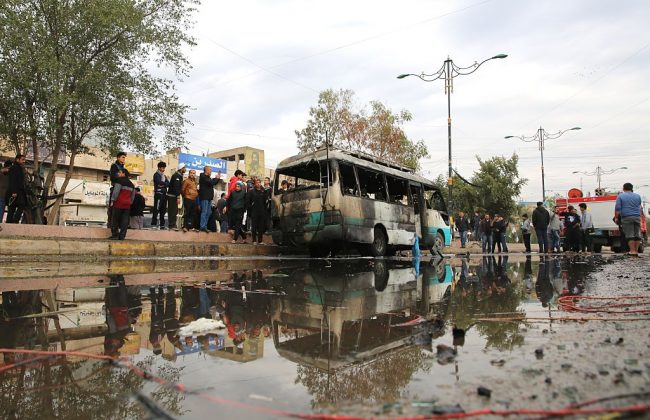 People gather around a wrecked vehicle following a blast, caused by a bomb-laden vehicle, at 55th Square in Sadr Region of Baghdad, Iraq on January 2, 2017. 