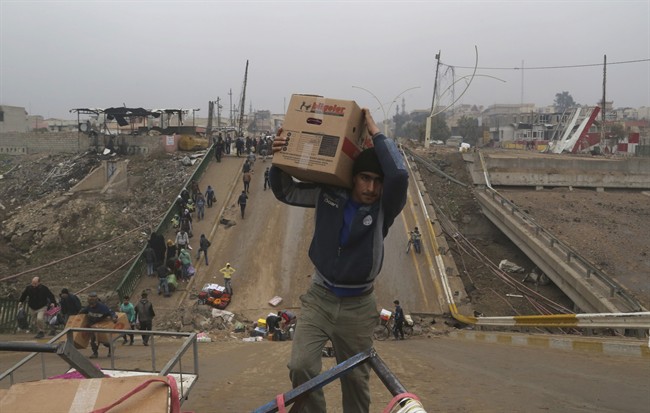 People cross a bridge destroyed by Islamic State militants in a neighborhood recently liberated from Islamic State on the eastern side of Mosul, Iraq, Sunday, Jan. 15, 2017. (AP Photo/ Khalid Mohammed).