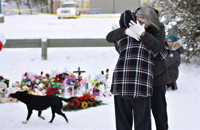 Residents console each other at the memorial near the La Loche Community School in La Loche, Sask., on Sunday January 24, 2016. Leaders in a remote Saskatchewan community will speak today about the recovery from a deadly school shooting that happened almost a year ago.