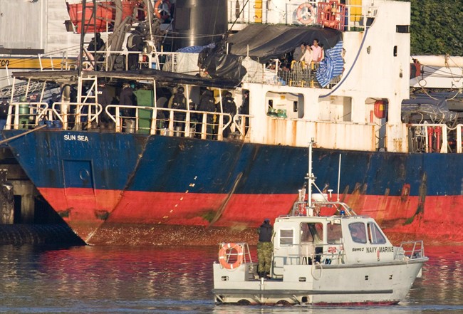 Migrants look over the side of the MV Sun Sea after it was escorted into CFB Esquimalt in Colwood, B.C., on Friday, Aug. 13, 2010. A jury in Vancouver is expected to begin deliberations on Thursday in the case of four men accused of smuggling hundreds of Tamil migrants into Canada. d.