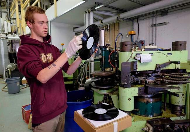 Jake Scott-Reid inspects a vinyl record as it comes off the press at Canada Boy Vinyl, the only vinyl record factory in Canada, at the facility in Calgary, Alta., Wednesday, Oct. 28, 2015. It appears one of the only vinyl record pressing plants in Canada has shut down its operations. Canada Boy Vinyl opened in Calgary in September of 2015 expecting to take advantage of a surge in vinyl record sales.