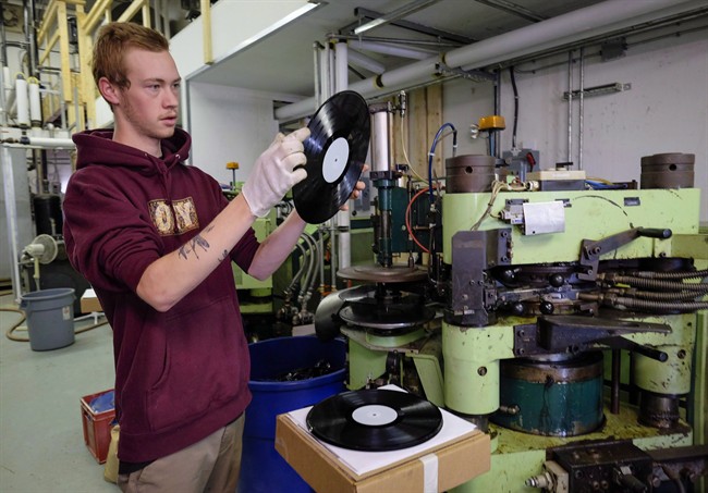 Jake Scott-Reid inspects a vinyl record as it comes off the press at Canada Boy Vinyl, the only vinyl record factory in Canada, at the facility in Calgary, Alta., Wednesday, Oct. 28, 2015. It appears one of the only vinyl record pressing plants in Canada has shut down its operations. Canada Boy Vinyl opened in Calgary in September of 2015 expecting to take advantage of a surge in vinyl record sales.