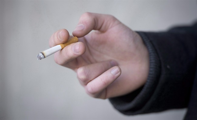 A smoker is seen holding his cigarette during a smoke break outside a building in North Vancouver, B.C. Monday, Jan. 20, 2014. 