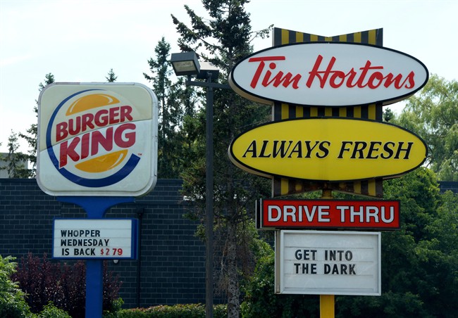 A Burger King sign and a Tim Hortons sign are displayed on St. Laurent Boulevard in Ottawa on Monday, August 25, 2014. The parent company of Tim Hortons and Burger King plans to launch an app Canada-wide this spring that would allow customers to order and pay in advance on their smartphone without lining up to pay a cashier. Since late December, the app has undergone testing in 25 Tim Hortons cafes in Ontario and 25 Burger King restaurants in Miami. The expansion would see the app rolled out to the roughly 4,000 Tim Hortons and Burger King locations across Canada. THE CANADIAN PRESS/Sean Kilpatrick.