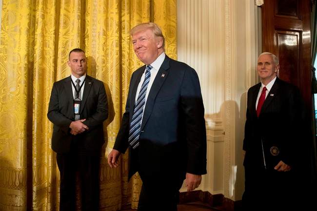 President Donald Trump, center, accompanied by Vice President Mike Pence, right, arrives for a White House senior staff swearing in ceremony in the East Room of the White House, Sunday, Jan. 22, 2017, in Washington.