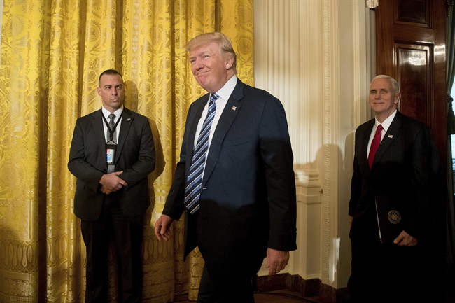 President Donald Trump, center, accompanied by Vice President Mike Pence, right, arrives for a White House senior staff swearing in ceremony in the East Room of the White House, Sunday, Jan. 22, 2017, in Washington.
