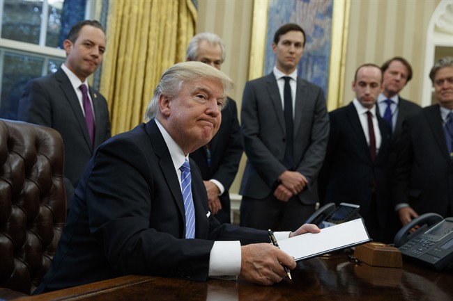 President Donald Trump looks up after signing the final of three executive orders, Monday, Jan. 23, 2017, in the Oval Office of the White House in Washington. 