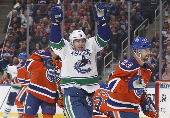 Vancouver Canucks' Alex Burrows (14) celebrates a goal as Edmonton Oilers' Matt Hendricks (23) skates by during third period NHL action in Edmonton, Alta., on Saturday December 31, 2016.