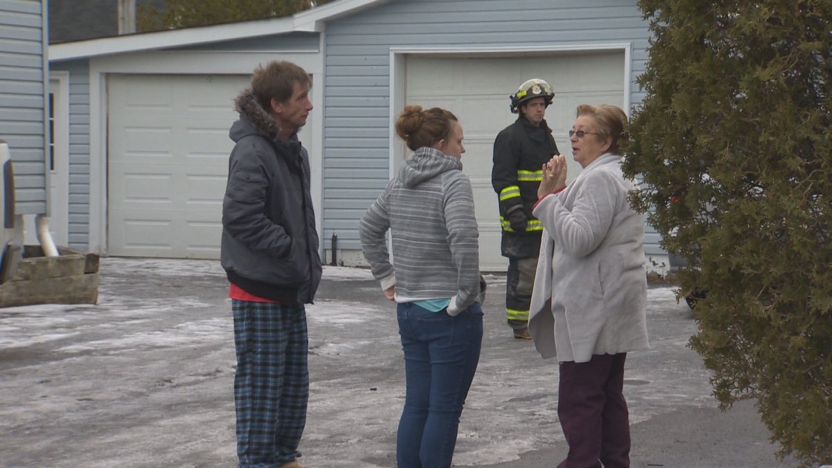 Survivors of a Saint John house fire stand outside hours after flames extensively damaged the home.